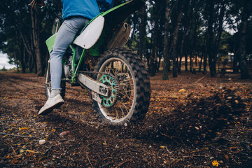 Male teenager spinning motorcycle tire while blowing dirt in forest
