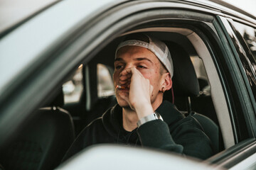 Young man smoking cigarette while driving car