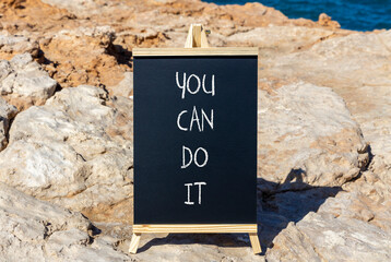 You can do it symbol. Concept word You can do it on beautiful black chalk blackboard. Beautiful red stone blue sea background. Business motivational you can do it concept. Copy space.