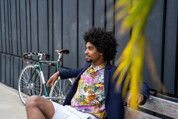 Stylish man with bicycle sitting on a bench - obrazy, fototapety, plakaty