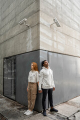Man and woman leaning on a wall, security cameras hanging over their heads