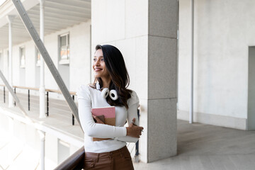 Smiling young woman holding notebook outdoors