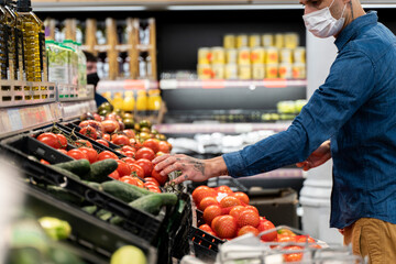 Midsection of man wearing face mask buying vegetables in supermarket