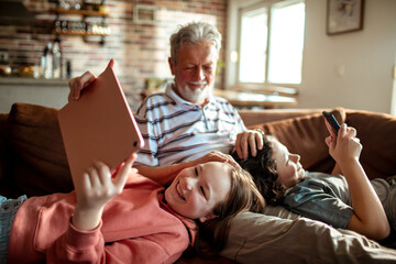 Grandfather and Grandchildren Enjoying Technology Together at Home