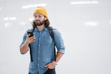 Portrait of man with backpack looking at smartphone