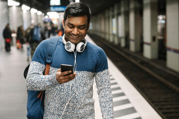 Smiling man using smartphone in subway station