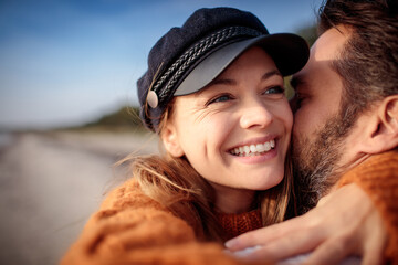 Close up smiling young woman in embrace of her loving husband at the beach