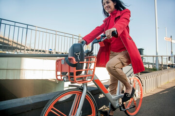 Young woman riding through the city on a rental bike