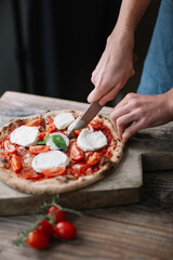 Young man preparing pizza, cutting pizza