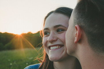 Portrait of teenage girl in love kissed by her boyfriend at sunset