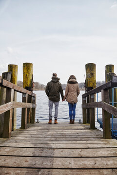 Germany, Potsdam, rear view of young couple standing on jetty at Havel River
