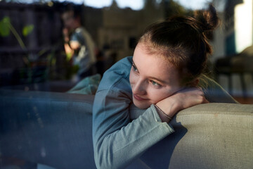 Girl on couch at home looking out of window