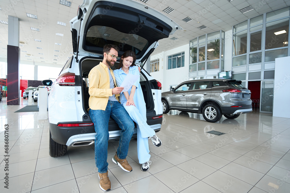 Wall mural photo of loving couple in car dealership