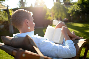 Woman on deckchair reading book in the garden