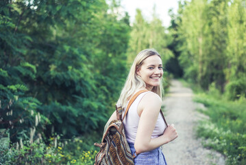 Portrait of smiling young woman with backpack on forest track
