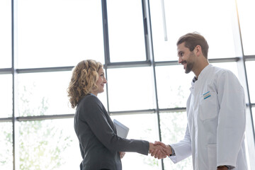 Businesswoman and doctor shaking hands in hospital - obrazy, fototapety, plakaty