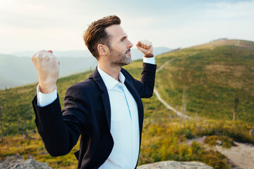 Self-confident businessman standing on top of a mountain - obrazy, fototapety, plakaty