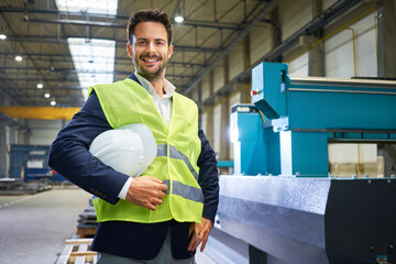 Portrait of smiling manager holding hard hat in factory