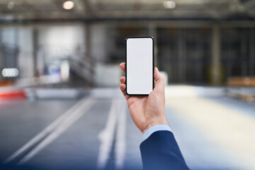 Close-up of businessman holding cell phone in factory