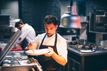 Chef serving food on a plate in the kitchen of a restaurant