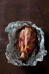 Roasted knuckle of pork in aluminium foil on a baking tray