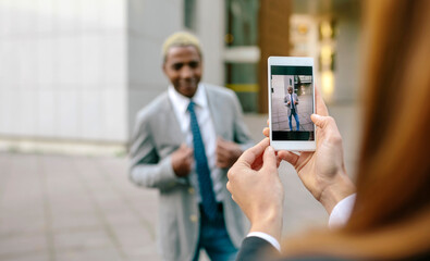 Young businessman and woman taking smart phone pictures