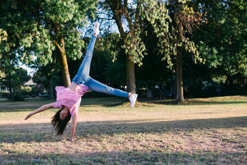 Girl doing cartwheel on land against trees in park
