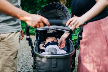 Parents standing by baby sleeping in carriage at park