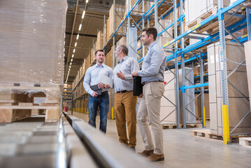Three men talking in factory warehouse