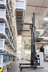 Worker operating forklift in factory warehouse