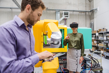 Colleagues in high tech company testing new technologies, using digital tablet and VR goggles