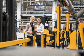 Two women with tablet talking in factory shop floor