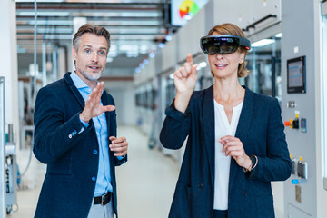 Businesswoman with AR glasses and businessman in a modern factory