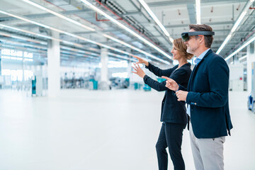 Businessman with AR glasses and businesswoman in a factory hall