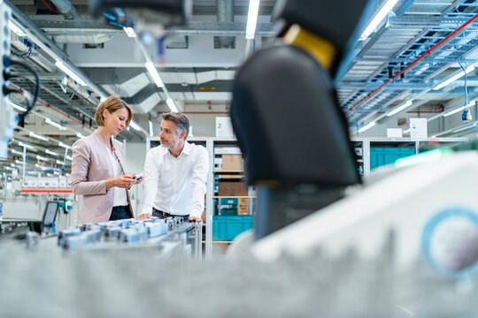 Businessman and businesswoman talking in a modern factory hall