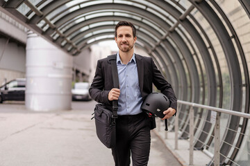Businessman with bag and helmet in the city on the go