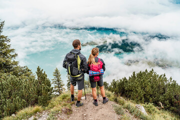 Young couple on a hiking trip in the mountains looking at view, Herzogstand, Bavaria, Germany - obrazy, fototapety, plakaty