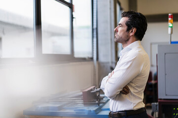 Pensive businessman in a factory looking out of window
