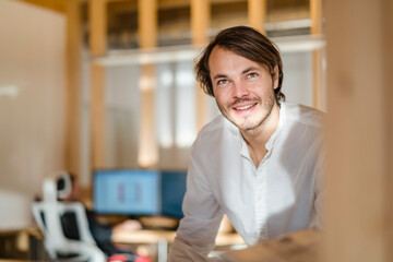Portrait of smiling businessman in wooden open-plan office