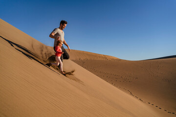 Father and daughter running down sand dune, Gran Canaria, Spain
