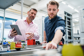 Two men with tablet having a work meeting in a factory