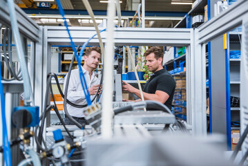 Two men having a meeting at a machine in factory