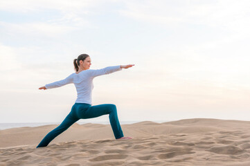 Woman practicing yoga at sunset in the dunes, Gran Canaria, Spain