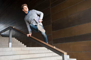 Young man jumping over railing at steps in underground walkway