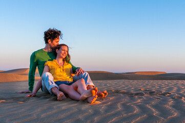 Affectionate couple sitting in the dunes at sunset, Gran Canaria, Spain
