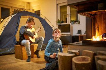 Brother and sister barbecueing and camping in the living room