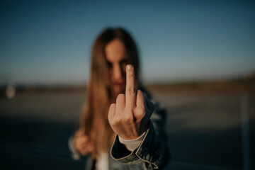 Close-up of young woman outdoors giving the finger