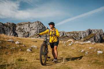 Fototapeta premium Mid adult woman holding bicycle while against mountain at Somiedo Natural Park, Spain