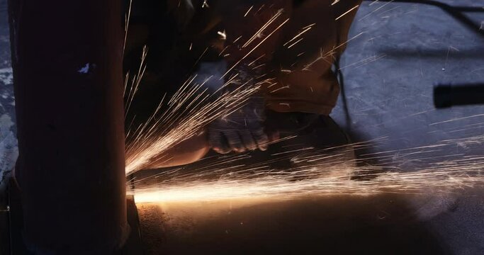While grinding iron worker cuts metal with an using abrasive disk processing spark