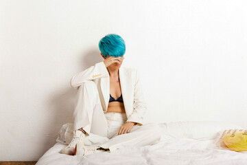 Grunge lesbian woman sitting pensive on bed - obrazy, fototapety, plakaty